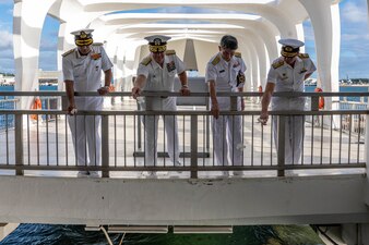 Leaders from Exercise Malabar toss flowers into the water to honor those lost aboard USS Arizona during a tour of the USS Arizona Memorial in Pearl Harbor.