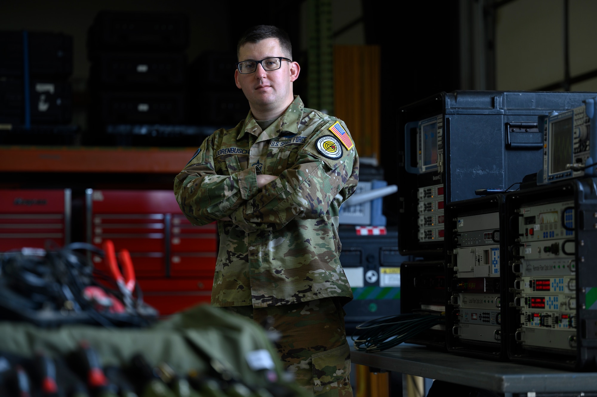 U.S. Space Force Master Sgt. Lane Dorenbusch, 527th Space Aggressor Squadron flight chief of weapons and tactics, poses for a portrait among training equipment inside the “Aggressor Barn” at Schriever Space Force Base, Colorado, April 7, 2023. The “Aggressor Barn” is a warehouse used to store and train on equipment, as well as a location to execute missions. Capable of operating from the “Barn” or in field training environments, Dorenbusch and his crew deploy adversary tactics to disrupt the satellite communications signals of friendly forces in order to prepare them for real-world threats. (U.S. Space Force photo by Paul Honnick)