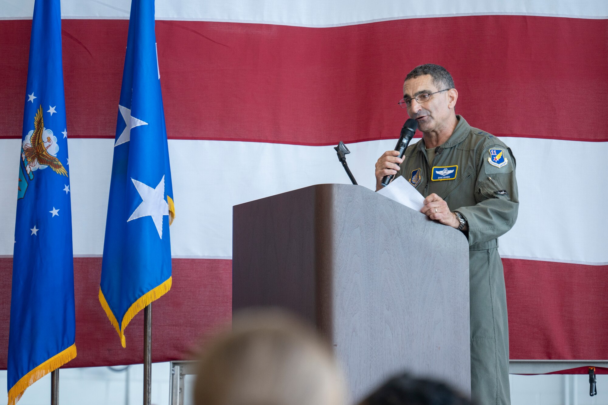 U.S. Air Force Lt. Gen. David Nahom speaks at a podium in front of a large American flag.