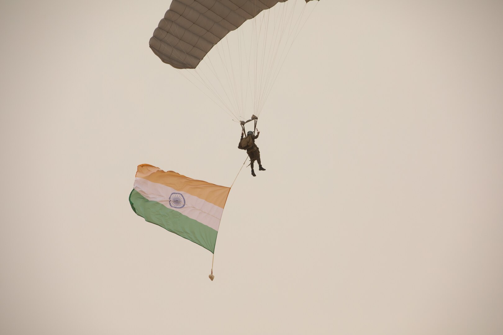A foreign soldier flies an Indian flag while parachuting.