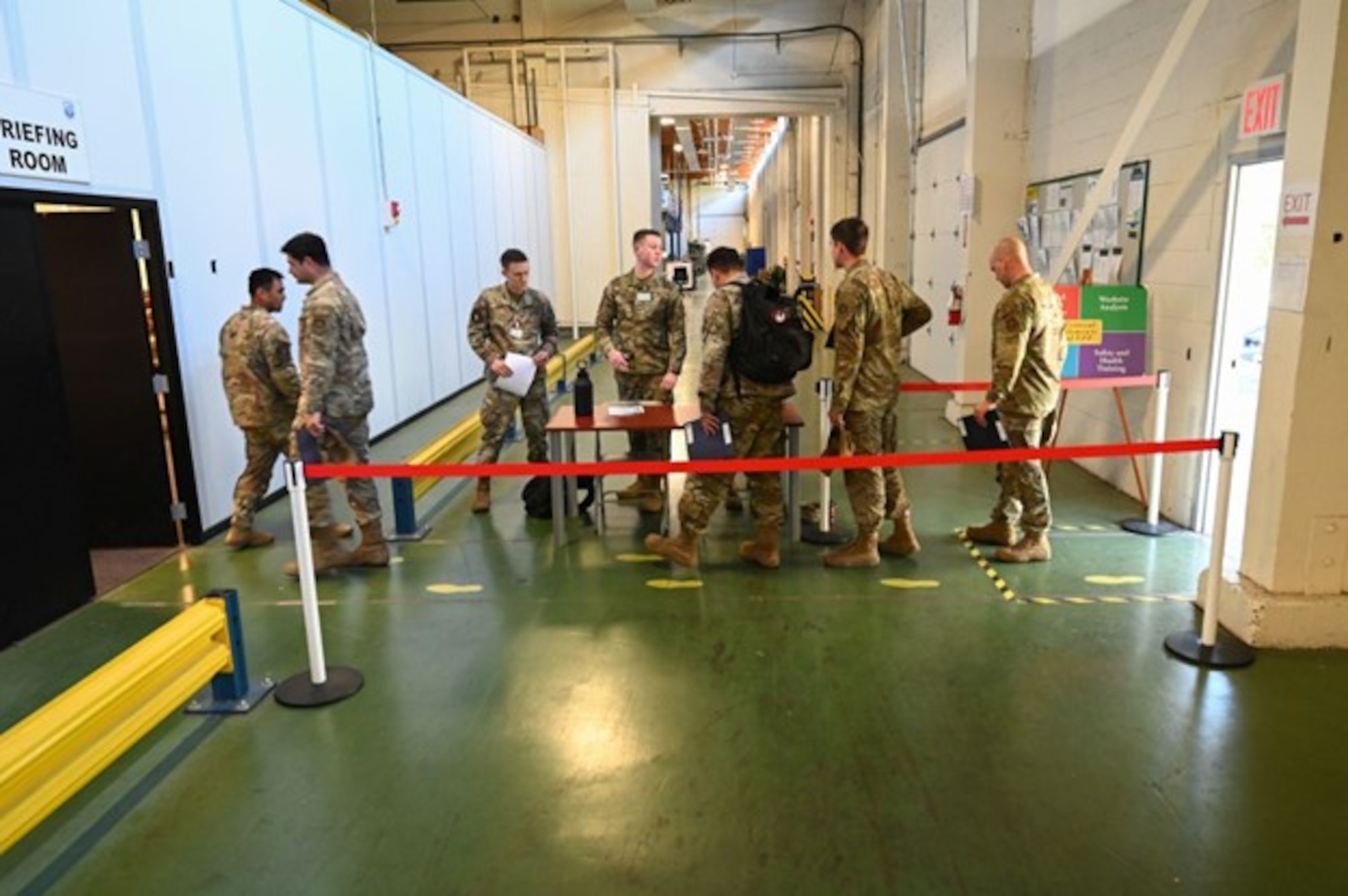 Team McChord Airmen enter a briefing room prior to deployment line processing during Exercise Rainier War 23A at Joint Base Lewis-McChord, Washington, Sept. 19, 2023. Rainier War is an exercise led by the 62d Airlift Wing designed to evaluate the ability to generate, employ and sustain in-garrison and forward deployed forces. These exercises are necessary in assessing and maintaining wartime operational tempos, ensuring command and control across multiple locations. During the exercise, Airmen will respond to scenarios that replicate today’s contingency operations and will address full-spectrum readiness against modern threats brought on by peer adversaries. (U.S. Air Force photo by Senior Airman Colleen Anthony)