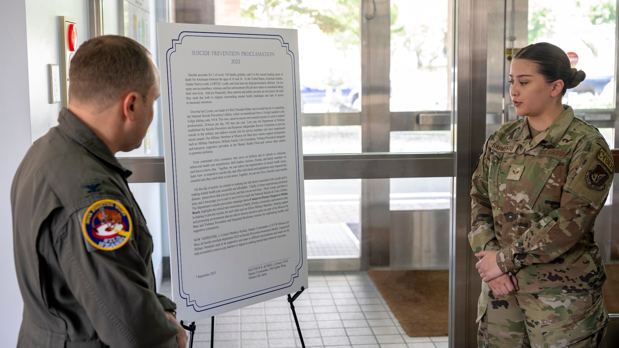U.S. Air Force Senior Airman Joelle Sarmiento, 35th Fighter Wing suicide prevention facilitator, reads Misawa’s 2023 Suicide Prevention Proclamation as Col. Matthew Kenkel, 35th FW deputy commander, prepares to sign the proclamation at Misawa Air Base, Japan.
