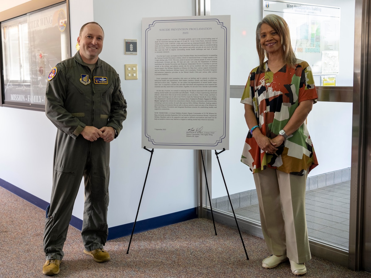 U.S. Air Force Col. Matthew Kenkel, 35th Fighter Wing deputy commander, and Andrea Bowen, 35th FW violence prevention integrator, stand beside Misawa’s 2023 Suicide Prevention Proclamation at Misawa Air Base, Japan.