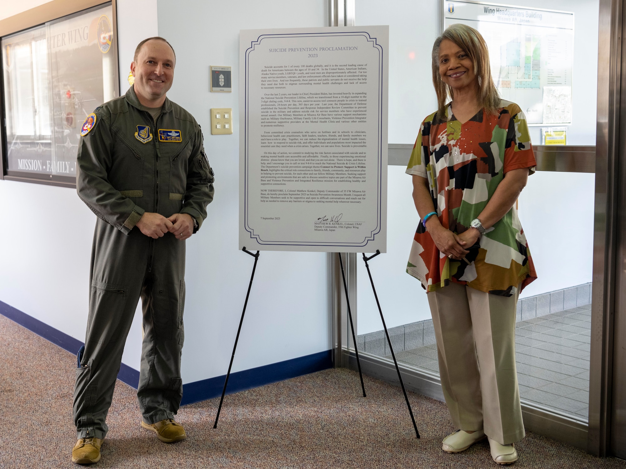 U.S. Air Force Col. Matthew Kenkel, 35th Fighter Wing deputy commander, and Andrea Bowen, 35th FW violence prevention integrator, stand beside Misawa’s 2023 Suicide Prevention Proclamation at Misawa Air Base, Japan.
