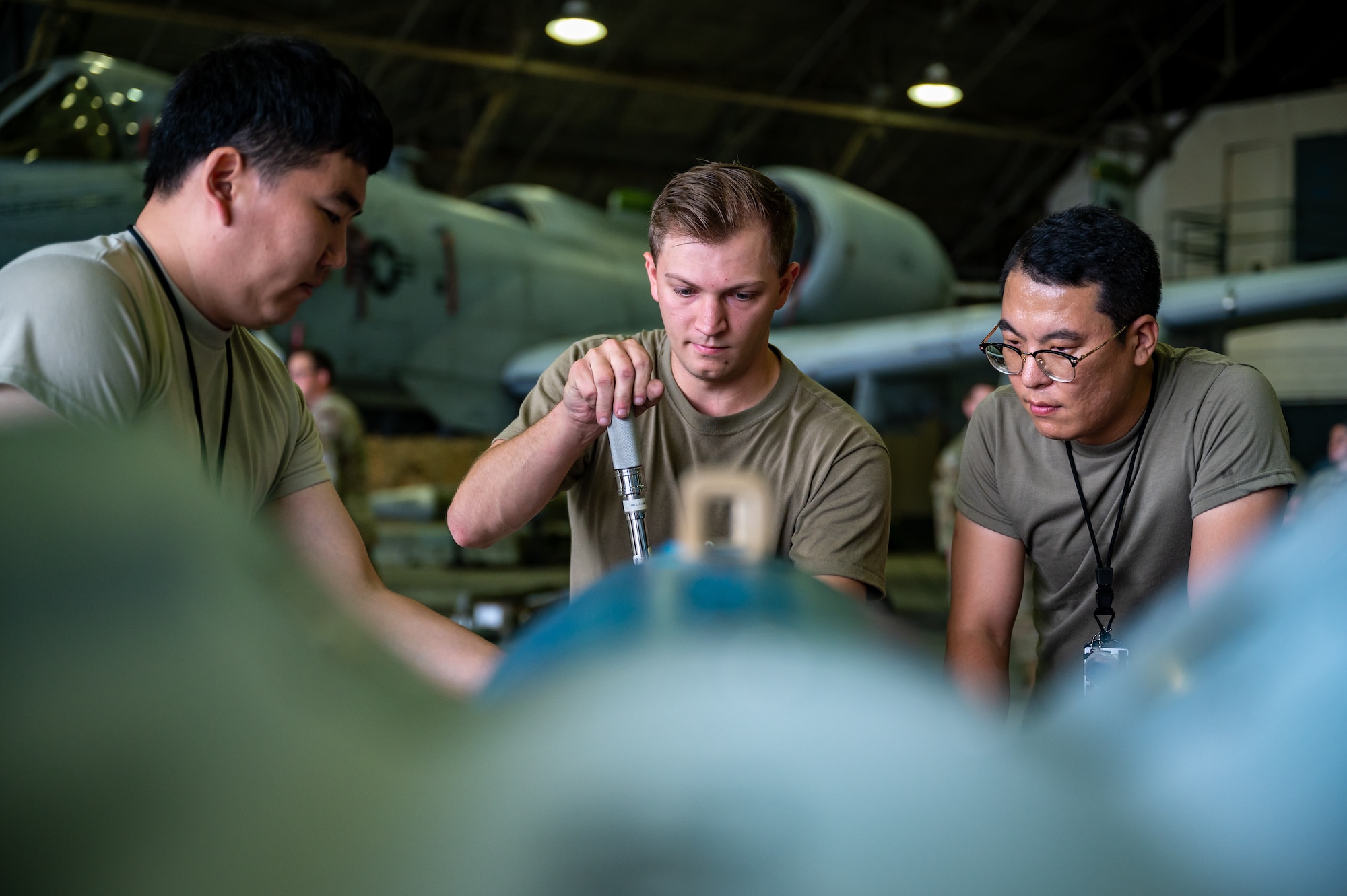 From the left, Tong Chu Paek, 51st Munitions Squadron explosives technician, U.S. Air Force Airman 1st Class Alexander Garten, 51st MUNS conventional maintenance technician, and Yong Sun Yi, 51st MUNS explosives technician, prepare munitions to be loaded during a quarterly load crew competition at Osan Air Base, Republic of Korea, Sept. 15, 2023. In a load crew competition, teams compete to load munitions onto an aircraft quickly and efficiently, aiming for the fastest completion time. Competitions create a realistic and stressful environment for Airmen, enhancing their skills to operate safely and efficiently in real-world scenarios. (U.S. Air Force photo by Staff Sgt. Thomas Sjoberg)