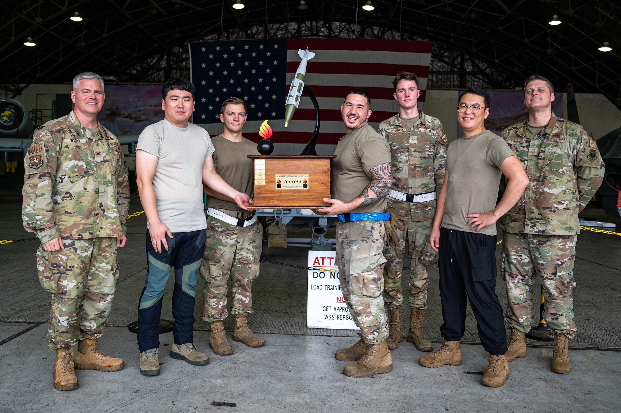 U.S. Air Force conventional maintenance technicians from the 51st Munitions Squadron pose for a group photo after winning a bomb building competition at Osan Air Base, Republic of Korea, Sept. 15, 2023. Before a load crew competition takes place, conventional maintenance technicians participate in a bomb-building competition. The munitions they construct are then loaded onto aircraft during the load crew competition, completing the real-world process from start to finish, creating comprehensive training, and enhancing interoperability between both career fields. (U.S. Air Force photo by Staff Sgt. Thomas Sjoberg)