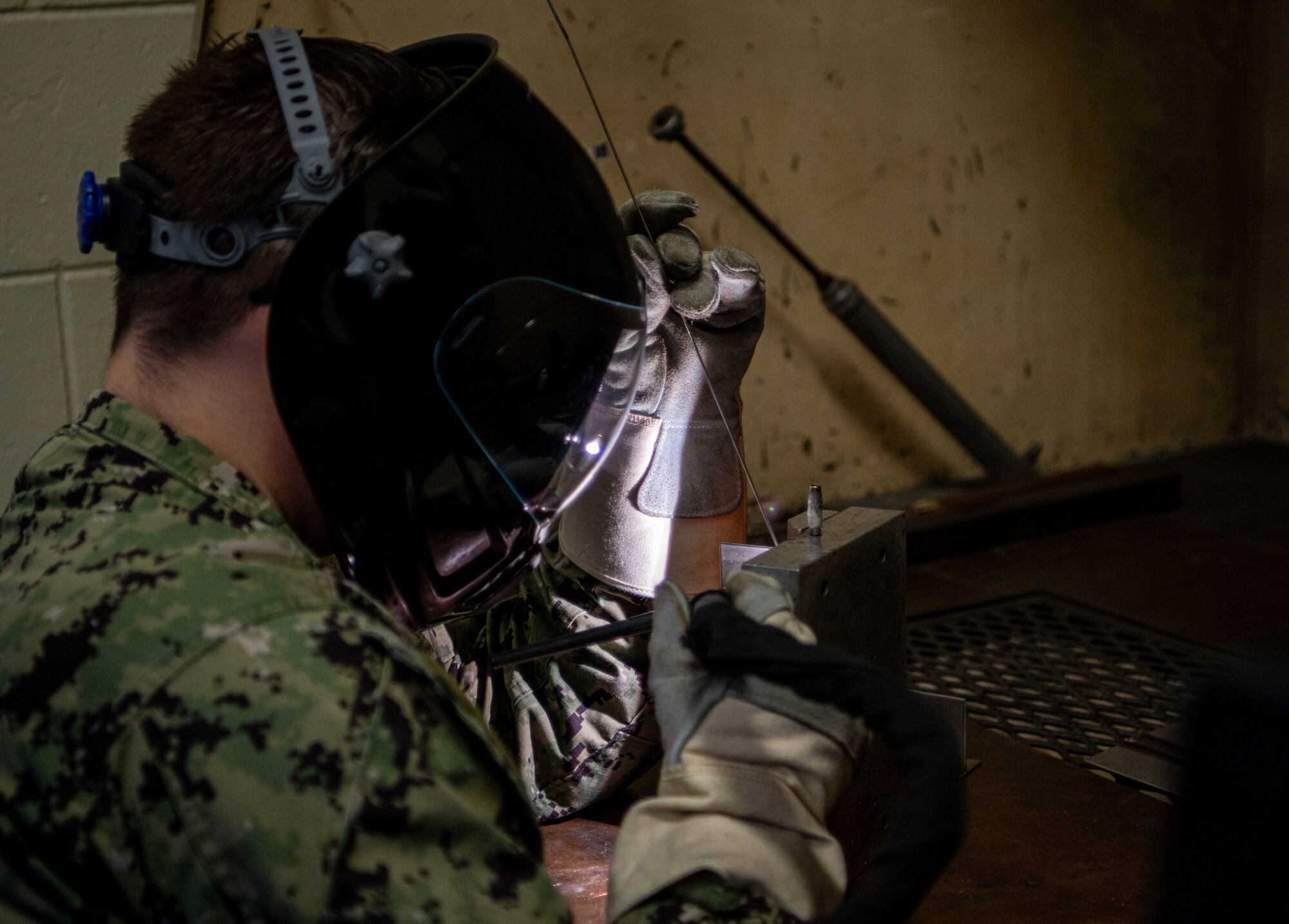 A U.S. Navy metals technician welds with a mask on.