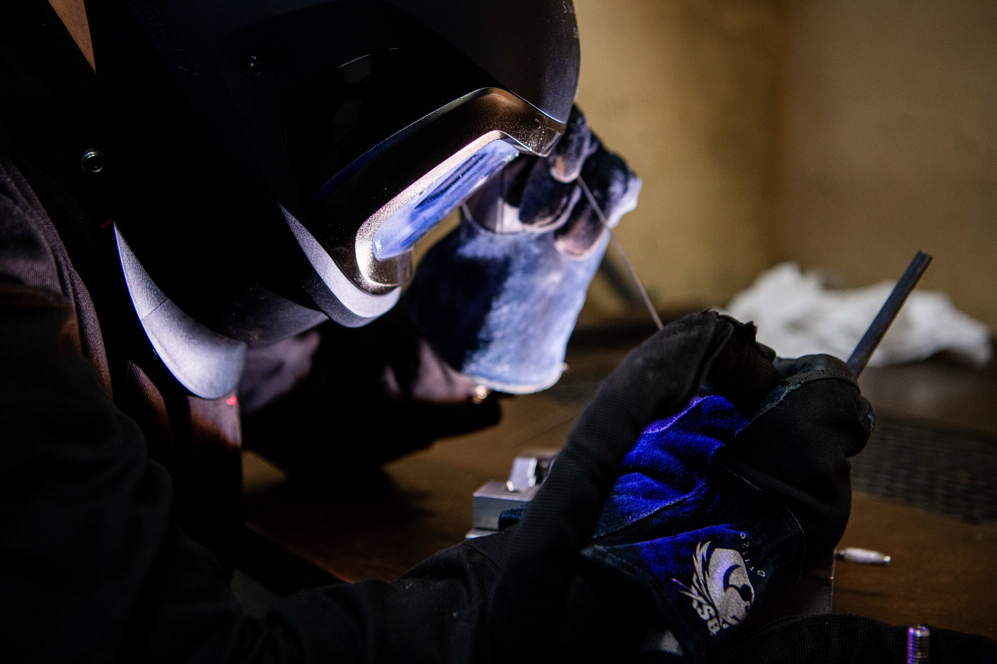 A metals technician welds with a mask on.