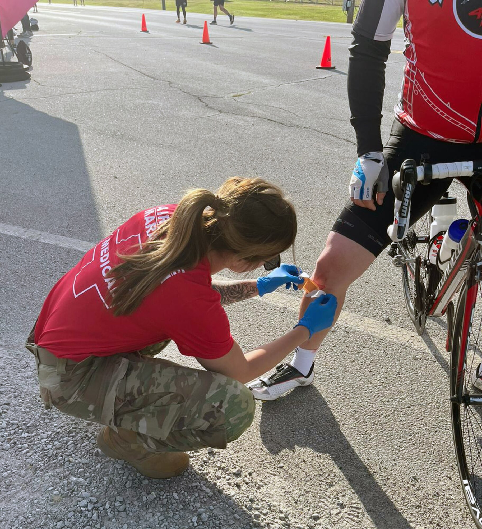 U.S. Air Force 1st Lt. Taylor Bone, 445th Aeromedical Staging Squadron, bandages a cyclist pacing marathon runners in Medical Tent F at mile marker 8 during the Air Force Marathon at Wright-Patterson Air Force Base Ohio, Sept. 16, 2023. The tent was located close to the 445th Airlift Wing section of the base and provided first aid and hydration. (Courtesy photo)