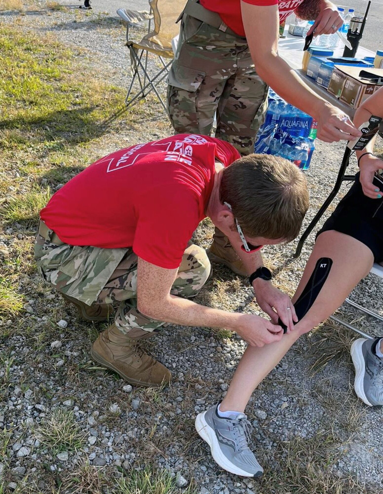 U.S. Air Force Capt. Daniel Shields, 445th Aeromedical Staging Squadron doctor, applies kinesio tape to a marathon runner experiencing leg cramping and pain Medical Tent F at mile marker 8 during the Air Force Marathon at Wright-Patterson Air Force Base, Ohio, Sept. 16, 2023. In addition to helping man the tent, Shields also ran in the marathon. (Courtesy photo)