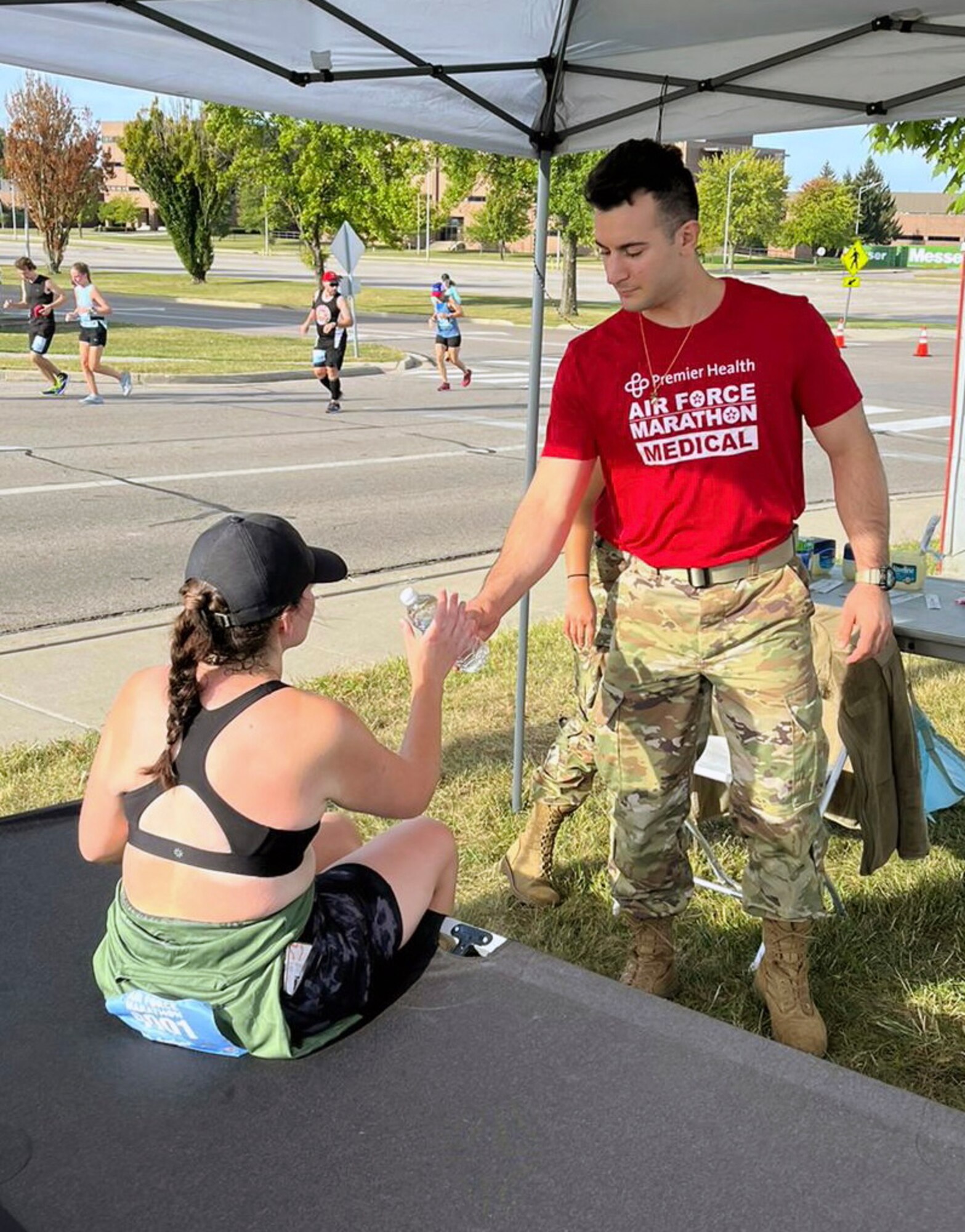 U.S. Air Force Staff Sgt. Philip Aliberti, right, 445th Aeromedical Staging Squadron, offers hydration to a marathon runner experiencing cramps in Medical Tent N between mile maker 20 and 21 during the Air Force Marathon at Wright-Patterson Air Force Base Ohio, Sept. 16, 2023. More than 8,000 runners competed in the marathon which included a half marathon, 10K run, 5K run and more in addition to the full marathon. (Courtesy photo)