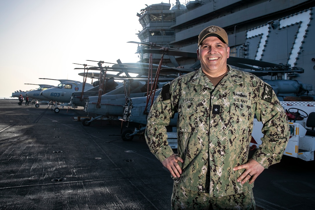 A man in military uniform stands on a ship deck