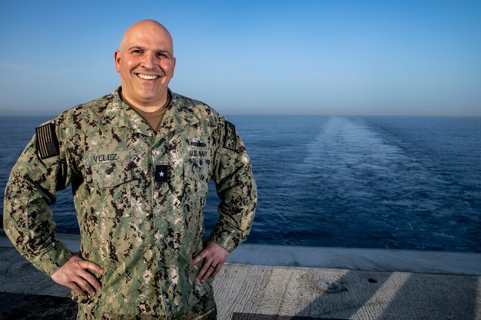 A man in military uniform stands on a ship deck