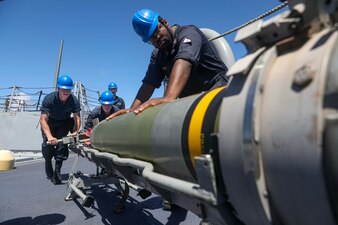 Sailors load a torpedo aboard USS Dewey (DDG 105) in the Philippine Sea.