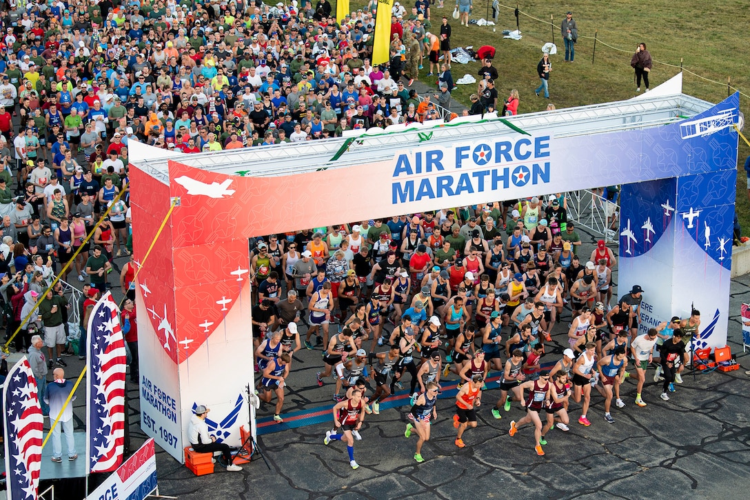 A large group of runners pour through the starting line at the Air Force Marathon.