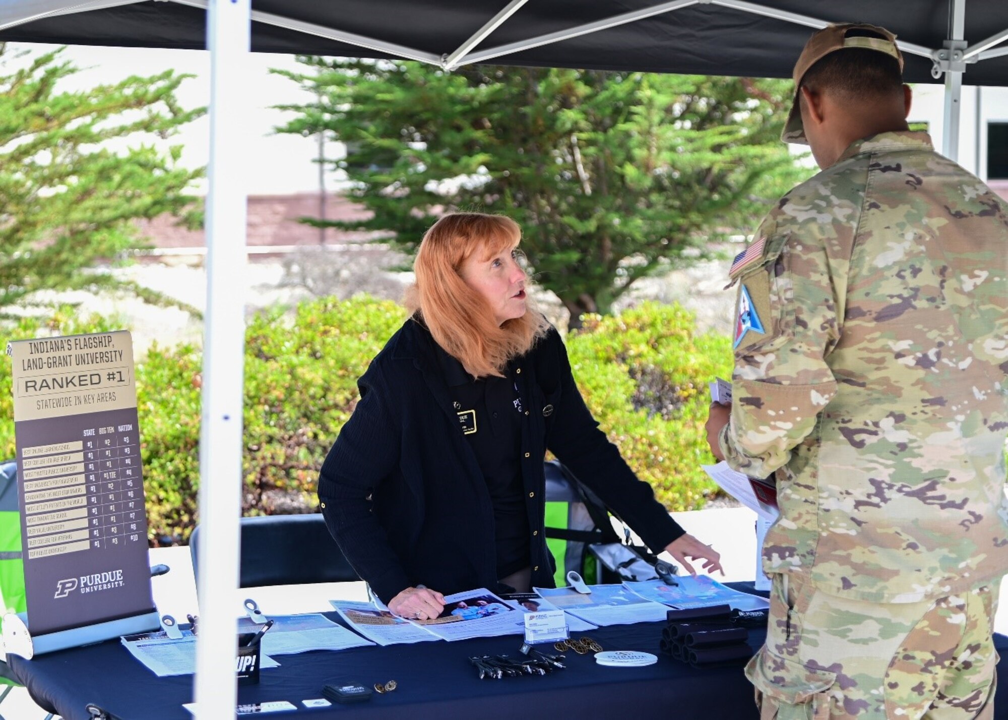 A representative from a university speaks to a person a military uniform.
