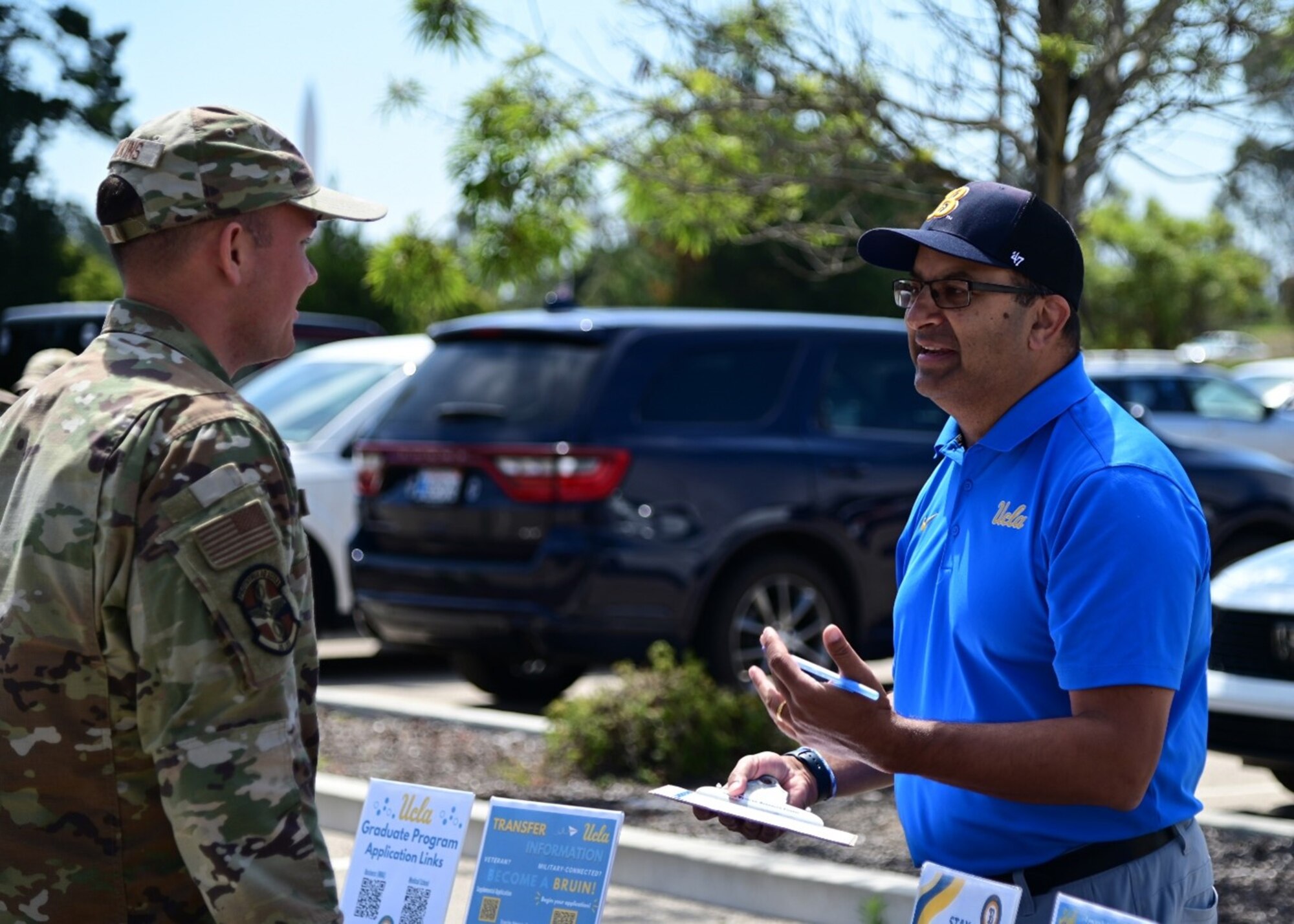 A man representing a university speaks to a man in a military uniform.
