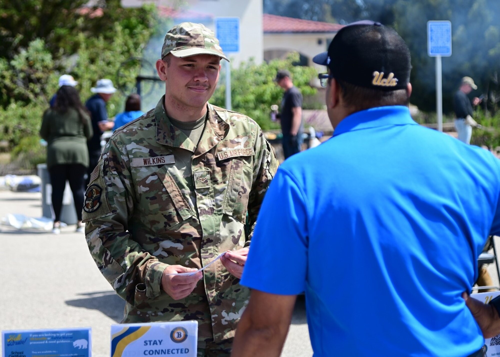 A man in uniform speaks with an individual representing a college.