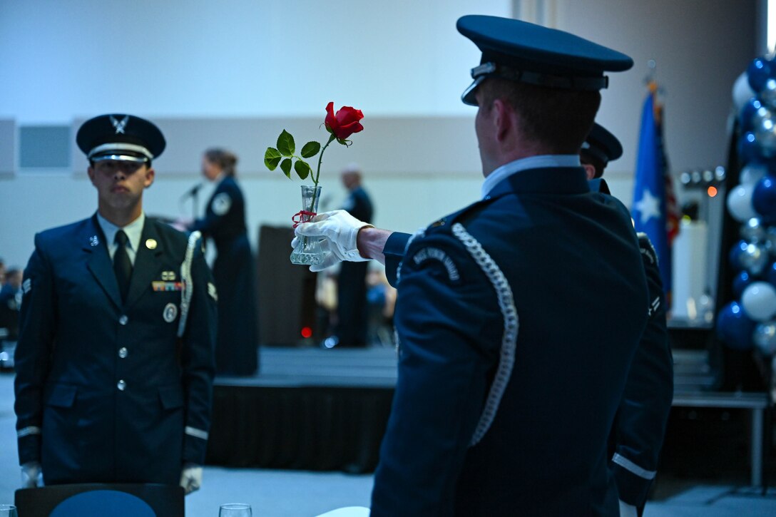 An Ellsworth Air Force Base Honor Guard member holds a vase with a red ribbon, containing a single red rose from the table reserved for POW/MIA members, at the Air Force Ball, Sept. 16, 2023, in Box Elder, South Dakota.
