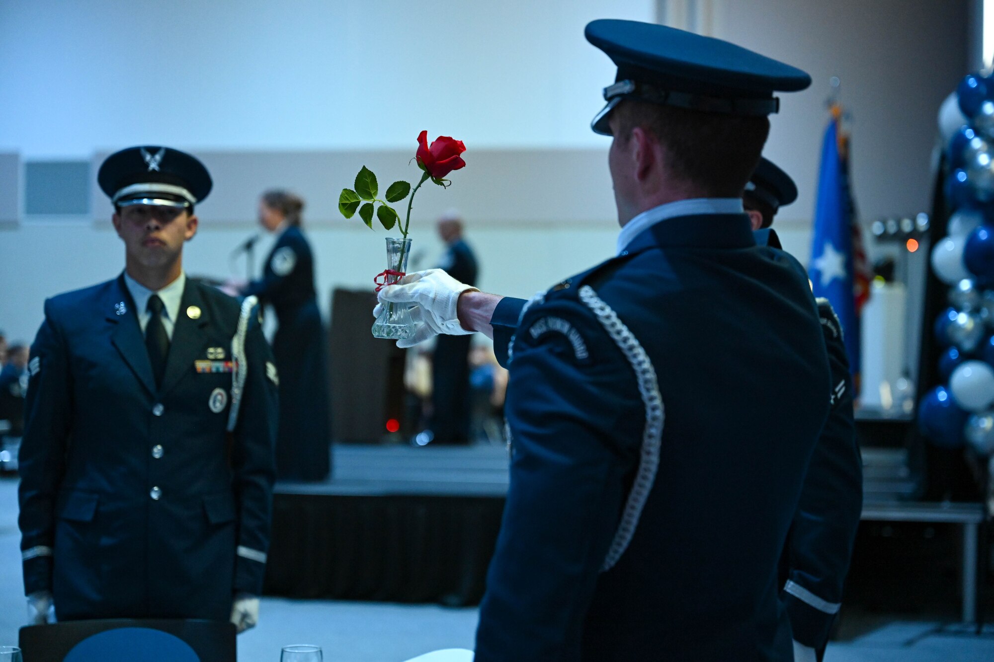 An Ellsworth Air Force Base Honor Guard member holds a vase with a red ribbon, containing a single red rose from the table reserved for POW/MIA members, at the Air Force Ball, Sept. 16, 2023, in Box Elder, South Dakota.