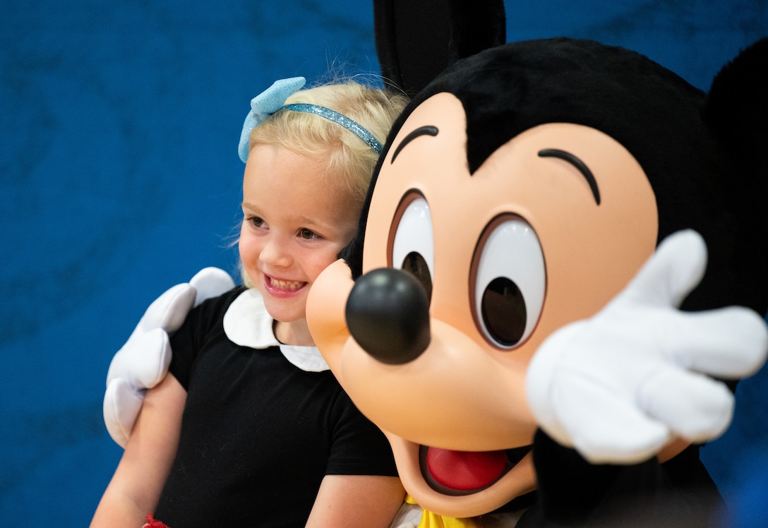 A military dependent takes a photo with Mickey Mouse