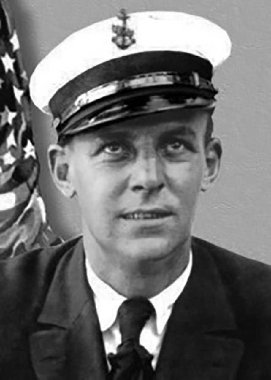 A person in dress uniform and cap poses for a black and white photo.