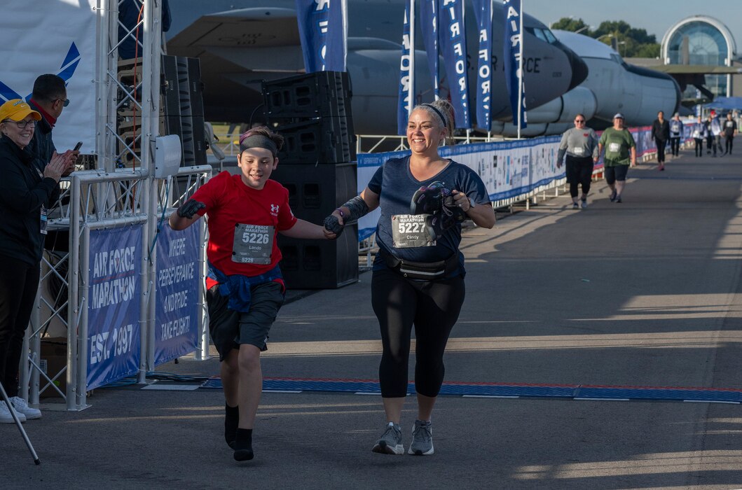 A boy and a woman hold hands as they cross the finish line.