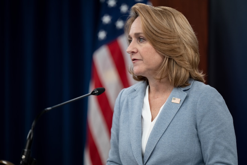 A woman speaks before a crowd of people.