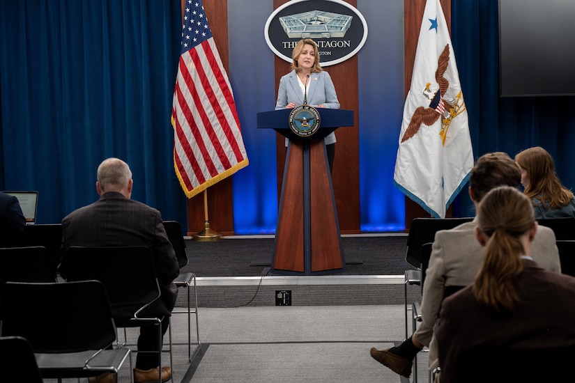 A woman speaks before a crowd of people.