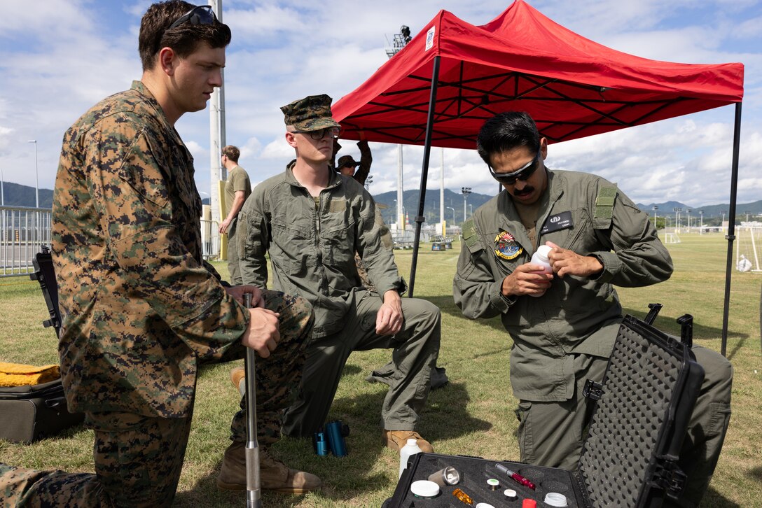 From left to right, U.S. Marine Corps Sgt. Matthew Mueller, an explosive ordnance disposal (EOD) instructor assigned to Headquarters and Headquarters Squadron, Marine Corps Air Station Iwakuni, Sgt. Alfred Delgado, and Sgt. Aidan Pedersen, explosive ordnance disposal EOD technicians assigned to Marine Wing Support Squadron 171, Marine Aircraft Group 12, 1st Marine Aircraft Wing, set up a percussion actuated neutralizer (PAN) during suspicious package ordnance training at Marine Corps Air Station Iwakuni, Japan, August 30, 2023. The MCAS Iwakuni EOD team conducts live-fire practical applications to refine individual and collective technical proficiency in the employment of improvised explosive device disruption tools and techniques. (U.S. Marine Corps photo by Cpl. Isaac Orozco)