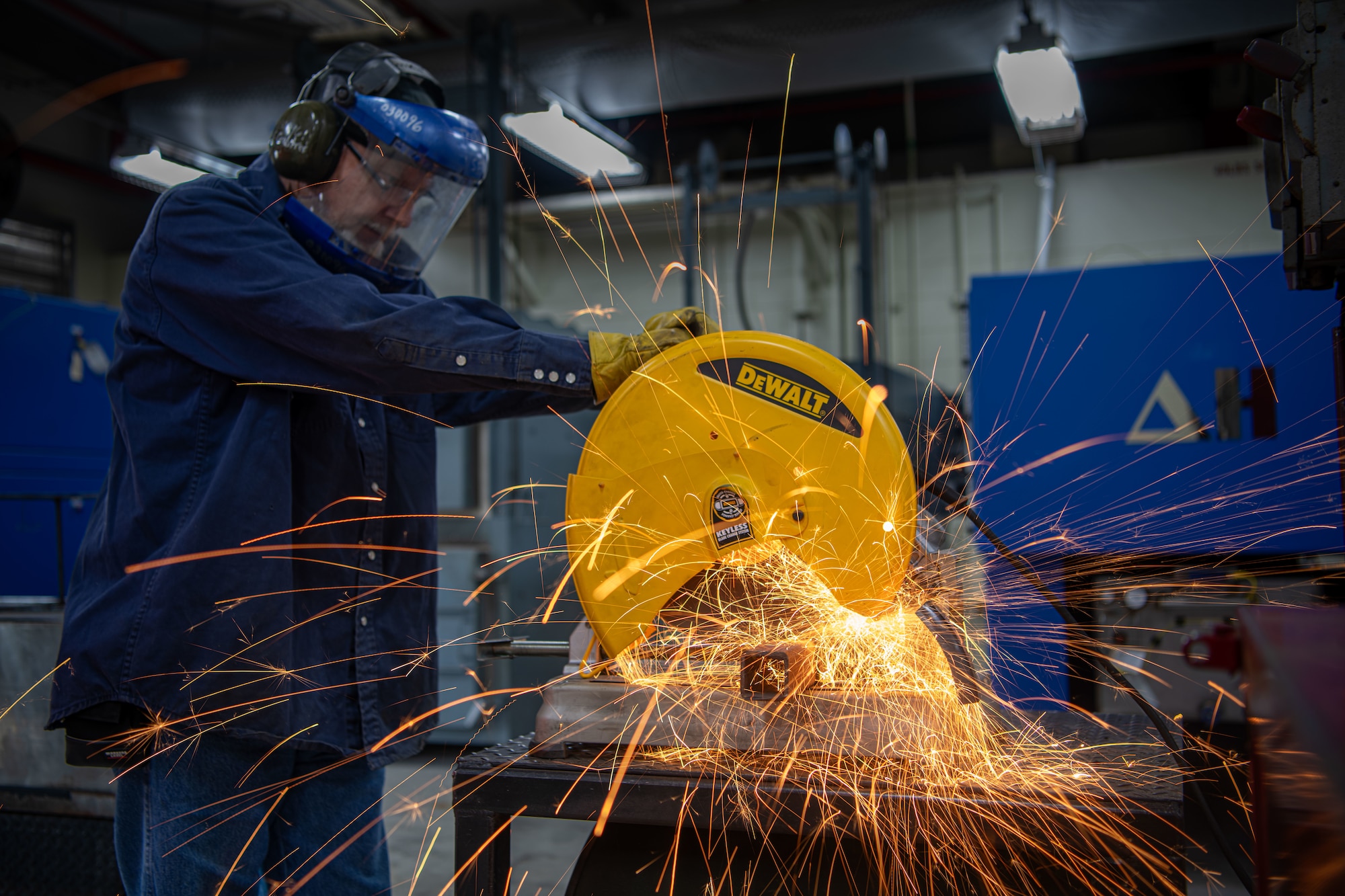 Metals technician cuts a piece of metal and sparks fly everywhere.