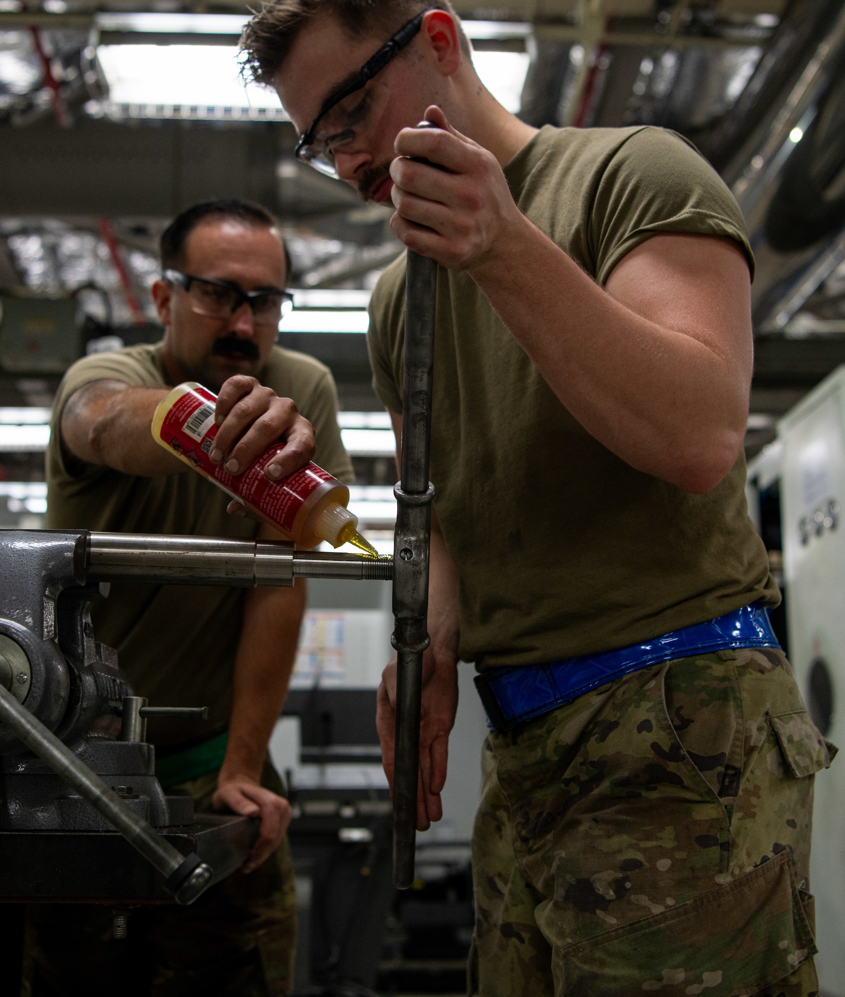 Two metals technicians fabricate and test a metal nut