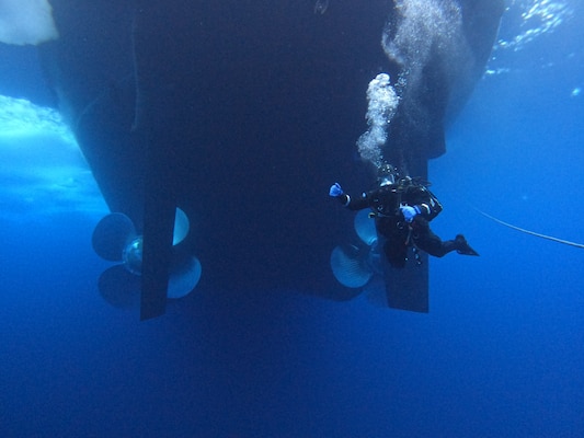 A military diver swims behind the icebreaker USCGC Healy (WAGB 20) during a scientific mission in the Beaufort Sea with USCG divers of Regional Dive Locker West and Navy divers of Mobile Dive and Salvage Unit (MDSU) 1 Aug. 11, 2023.