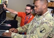 Maj. Brandon McCalla, a signal officer with U.S. Army Reserve Sustainment Command’s Detachment 7, familiarizes himself with the information system interfaces at Army Medical Logistics Command headquarters during a recent training assignment at Fort Detrick, Maryland. Also pictured is Matt Tyler, desktop support lead for AMLC’s G-6. (C.J. Lovelace)