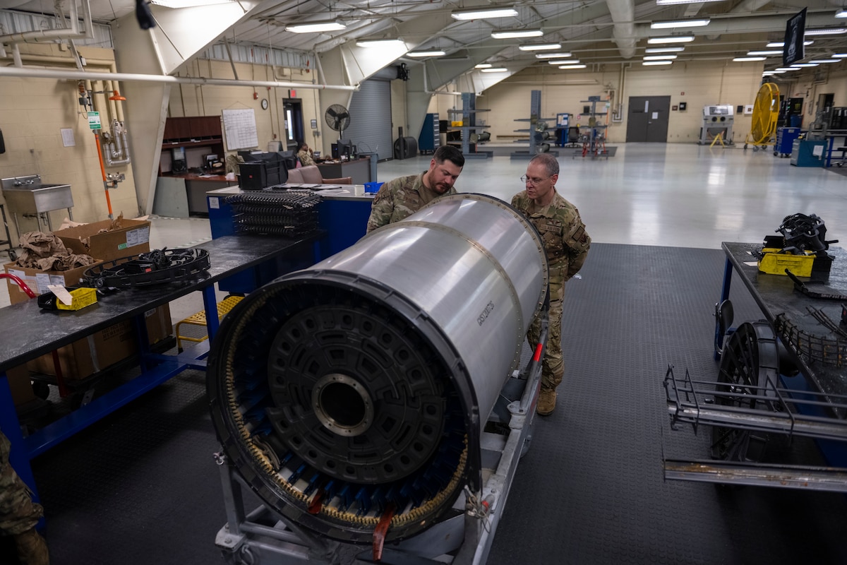 A photo of two people standing next to a large piece of machinery in a warehouse.