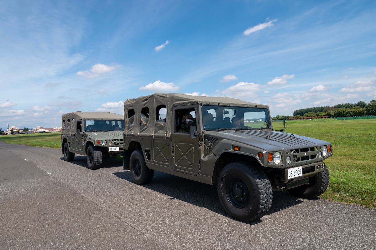 Japan Ground Self-Defense Force high-mobility vehicles park on a road during a training scenario