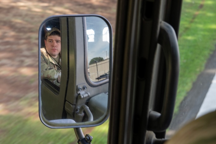 A U.S. Air Force Airman looks through the side mirror of a vehicle