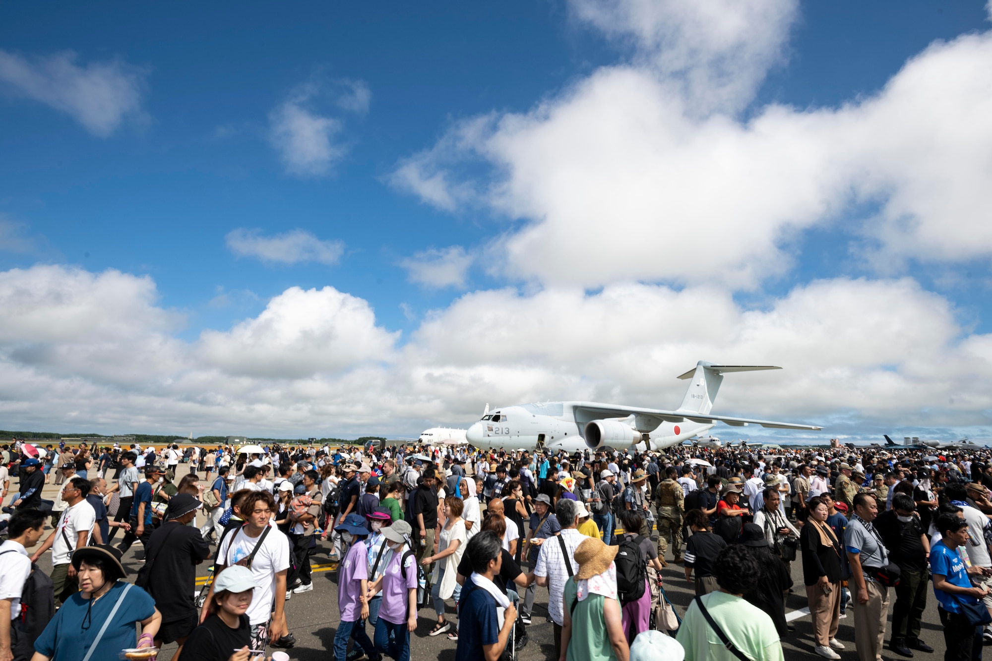 A photo of a plane parked on the runway surrounded by a lot of people.