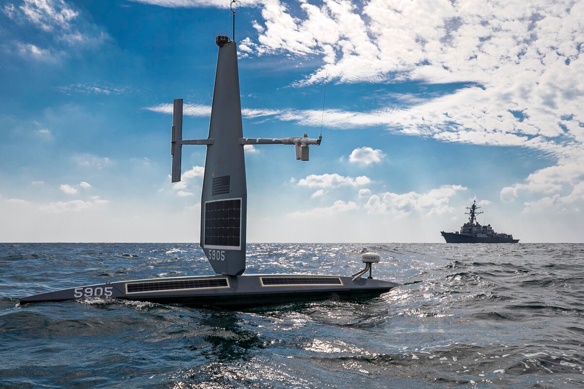 An unmanned vessel floats near a Navy destroyer.