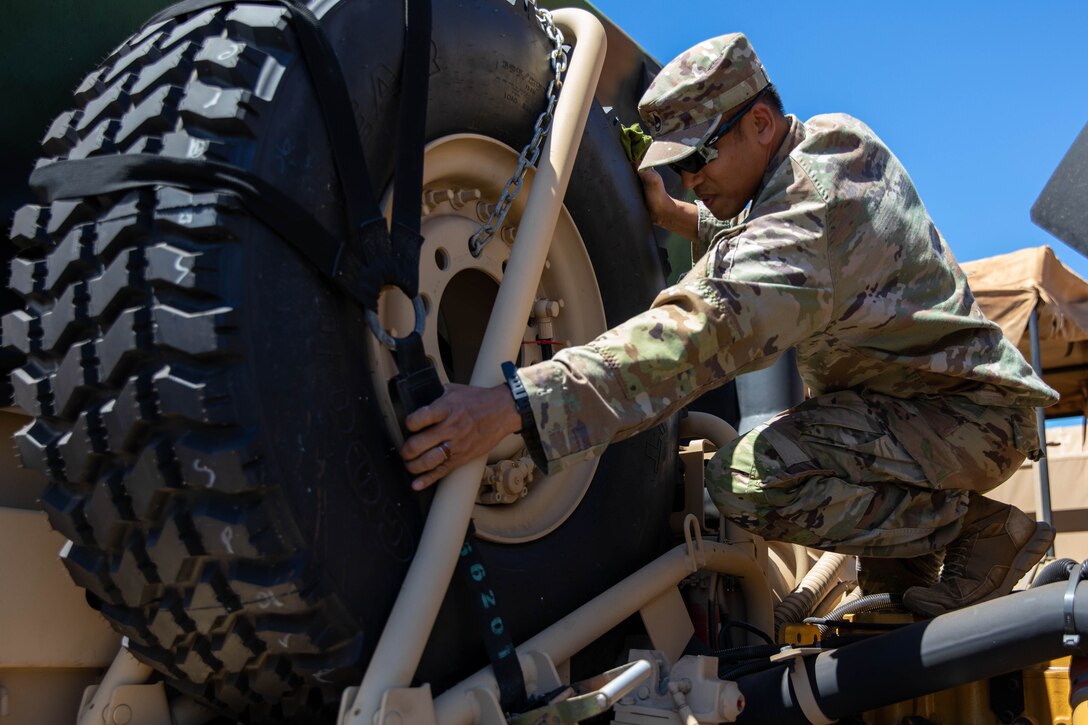 A soldier secures a tire of a vehicle.