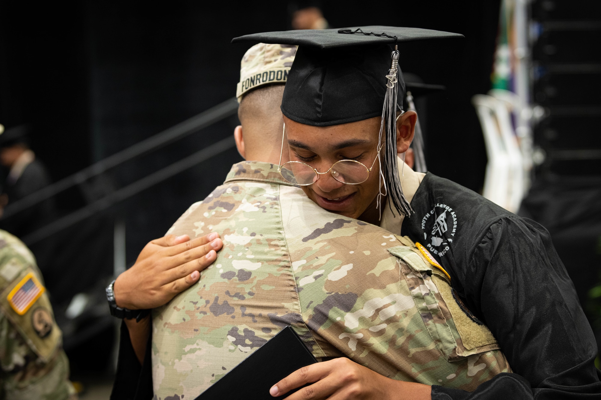 Cadet Jan Lopez with the Puerto Rico National Guard Youth ChalleNGe Academy, 3rd Platoon, Wolfpack, Class 23-02, hugs U.S. Army Staff Sgt. Axel I. Fonrodona, a cadre with the PRNG Youth ChalleNGe Academy, after receiving his graduation diploma during his class graduation ceremony at Pontifical Catholic University of Puerto Rico, Ponce, Puerto Rico, Sept. 15, 2023. Lopez received his high school diploma after completing the 22-week PRNG Youth ChalleNGe Academy program, where he studied for his high school diploma and also received vocational education from several career fields. (U.S. Air National Guard photo by 2nd. Lt. Eliezer Soto)