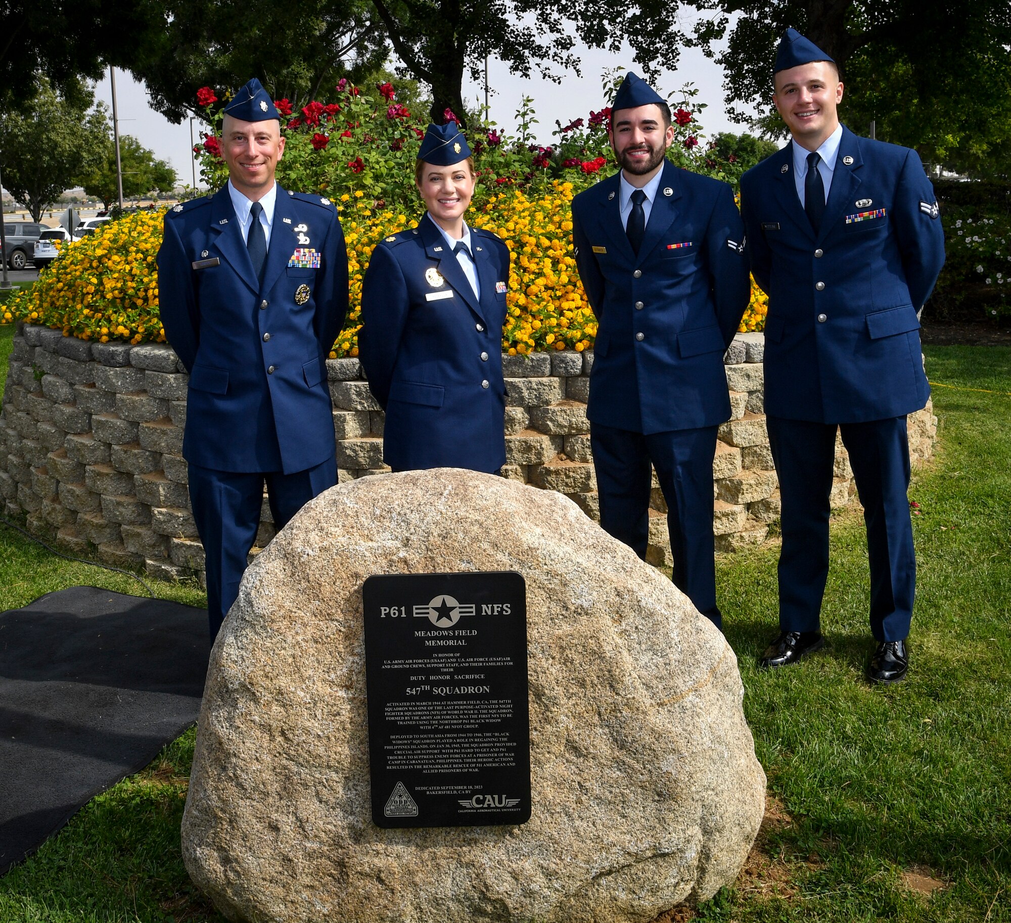 Four Airmen stand in front of a memorial plaque.