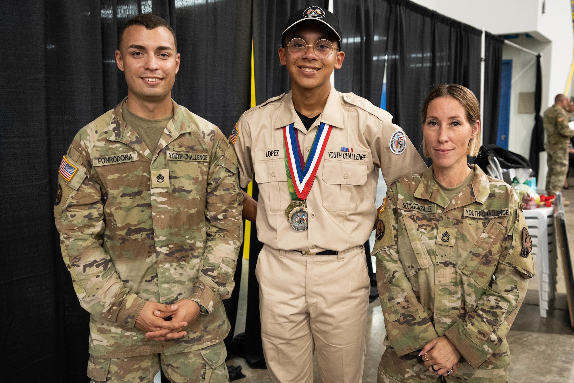 From left, U.S. Army Staff Sgt. Axel I. Fonrodona, a cadre with the Puerto Rico National Guard Youth ChalleNGe Academy, Cadet Jan Lopez with the PRNG Youth ChalleNGe Academy, 3rd Platoon, Wolfpack, Class 23-02, and U.S. Army Sgt. 1st Class Almaleynisse Soto, the cadre supervisor, 3rd Platoon, Wolfpack, Class 23-02, with the PRNG Youth ChalleNGe Academy pose for a photo after the graduation ceremony at Pontifical Catholic University of Puerto Rico, Ponce, Puerto Rico, Sept. 15, 2023. Lopez received his high school diploma after completing the 22-week PRNG Youth ChalleNGe Academy program, where he studied for his high school diploma and also received vocational education from several career fields. (U.S. Air National Guard photo by 2nd. Lt. Eliezer Soto)