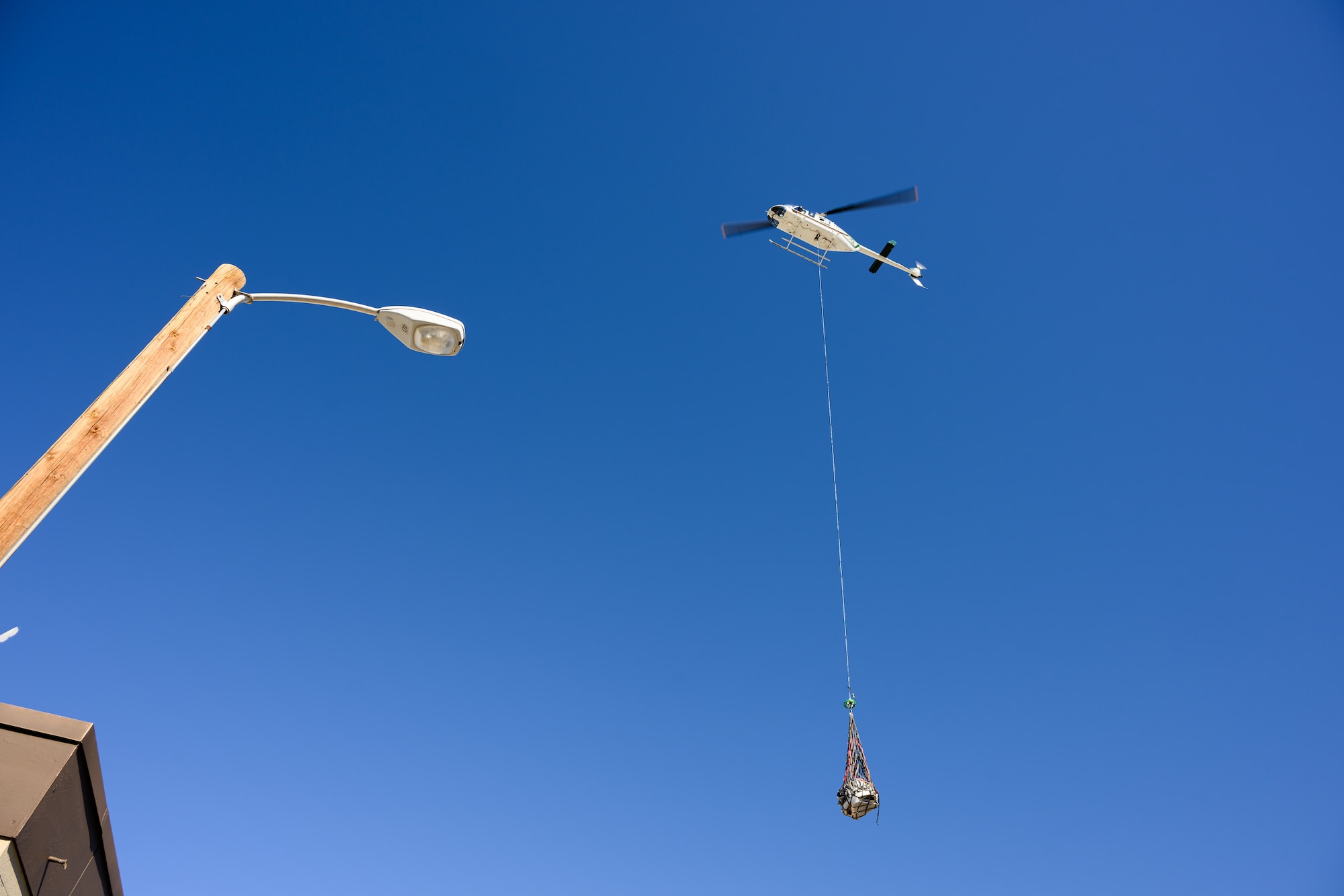 A photo of a capsule being lowered to the ground in a helicopter sling