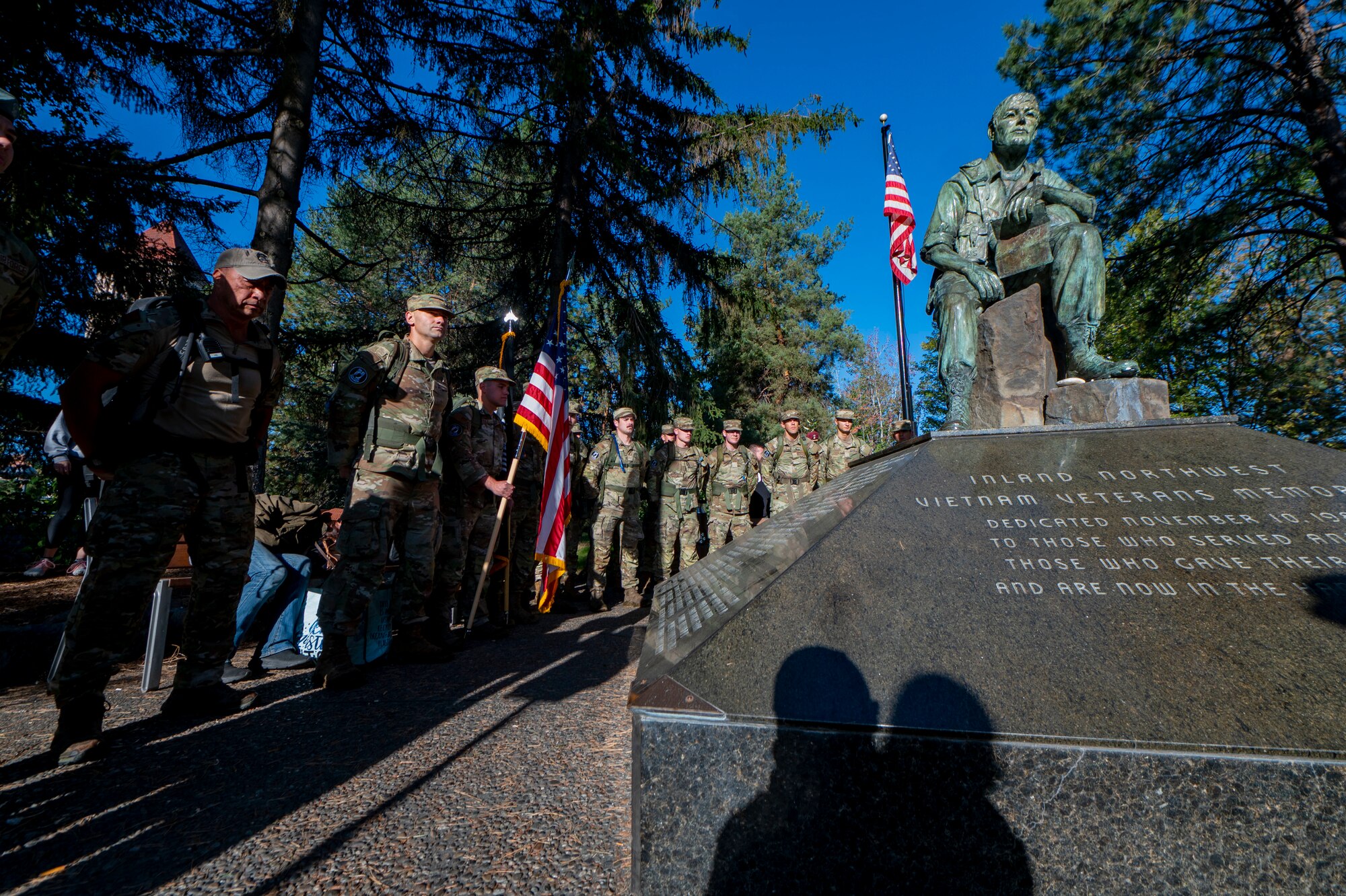 Del Rosario, left, a survival, evasion, resistance and escape candidate course instructor assigned to the 66th Training Squadron, and a formation of SERE candidates gather for opening remarks next to a Vietnam Veteran’s Memorial statue prior to beginning a 24-hour ruck march at Riverfront Park in Spokane, Washington, Sept. 14, 2023. Senior leaders from the 336th Training Group provided opening remarks, emphasizing the importance of honoring and recognizing those who became prisoners of war or are still unaccounted for as a result of war-time operations. During the ruck march, Airmen from Fairchild Air Force Base kept the Prisoner of War/Missing in Action flag in constant motion to honor National POW/MIA Recognition Day. The march began on Sept. 14 at the Vietnam Veterans Memorial in downtown Spokane and continued through Airway Heights before concluding at Fairchild AFB. The event culminated with a recognition ceremony on Sept. 15 to honor all American prisoners of war and those Americans still missing in action, as well as their families. Every year, the third Friday in September is recognized in the United States as National POW/MIA Recognition Day. The Department of Defense is steadfast in its commitment to finding, recovering, identifying and repatriating the remains of its heroes who are unaccounted for. (U.S. Air Force photo by Staff Sgt. Lawrence Sena)