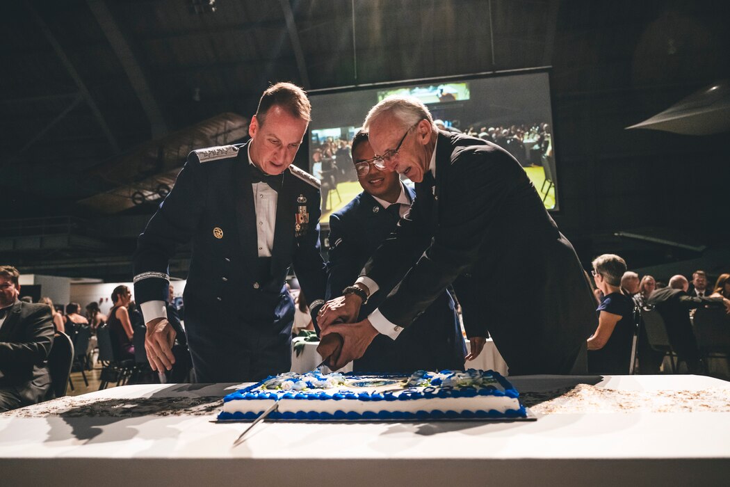 Three people cut a cake in honor of the Air Force's 76 Anniversary.