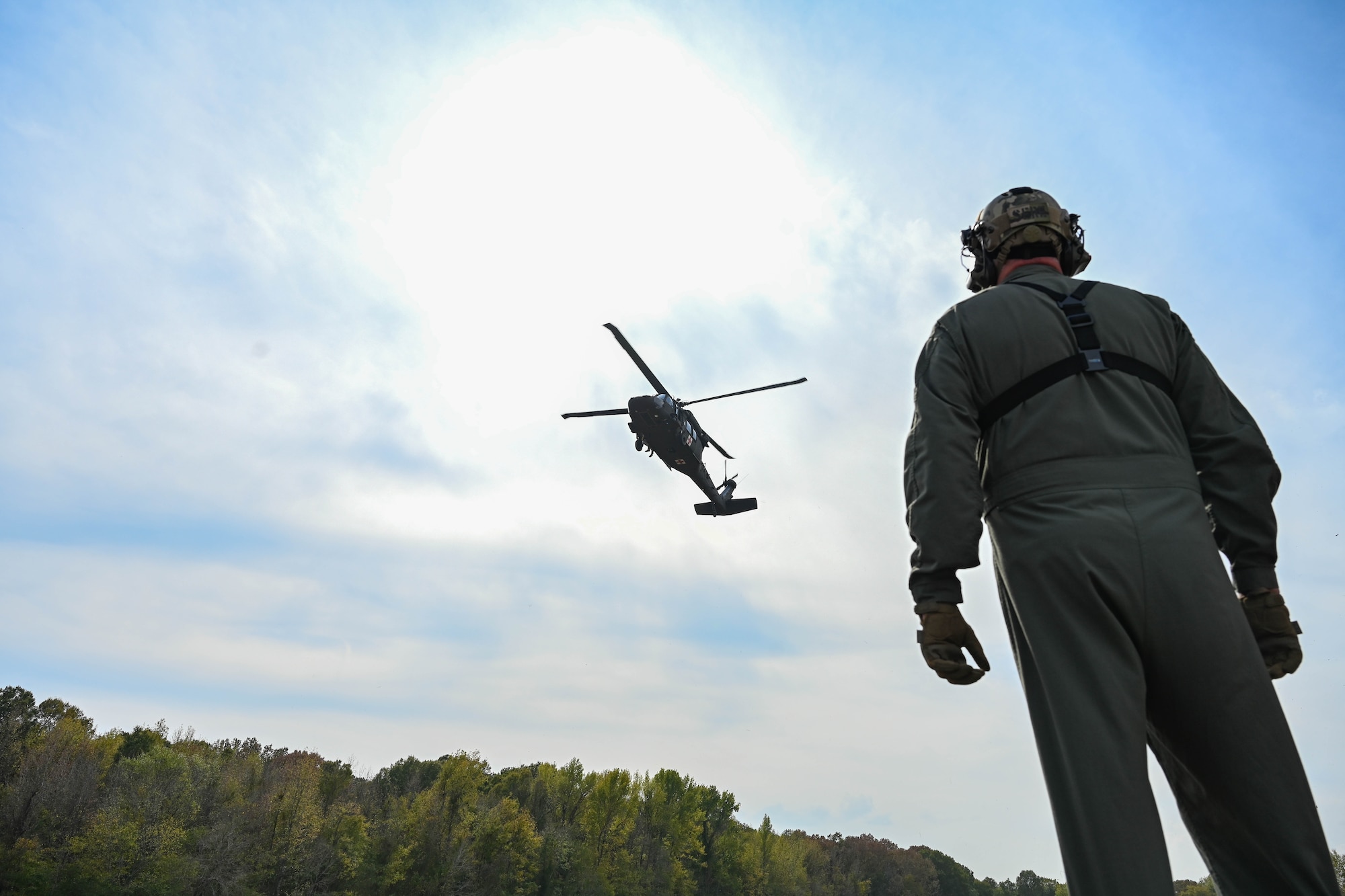 A man in uniform looks up at a helicopter