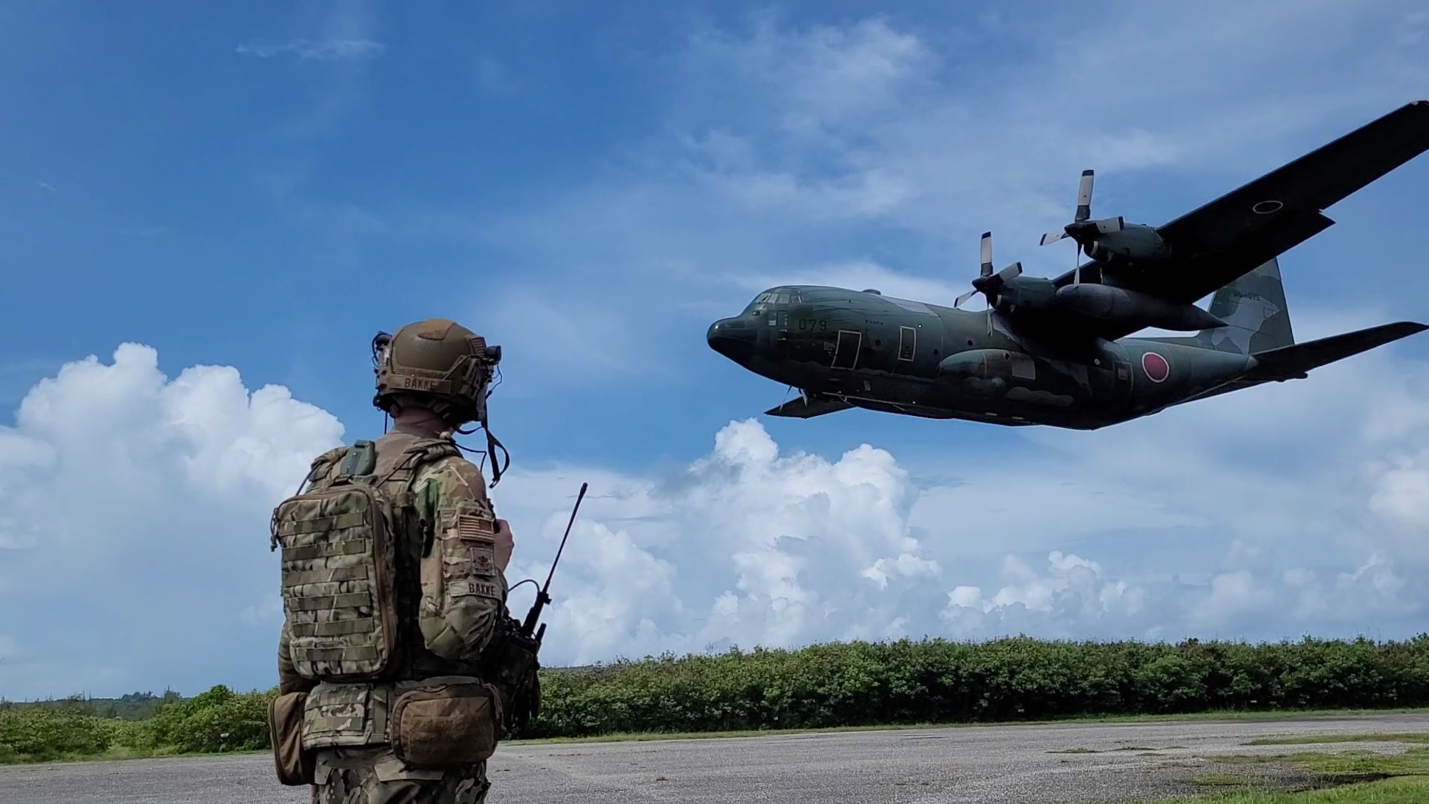 U.S. Air Force Maj. Michael Bakke from the 621st Mobility Support Operations Squadron, Joint Base McGuire-Dix-Lakehurst, New Jersey, prepares as a Japanese C-130 lands on Baker Landing Zone in Tinian, U.S. Commonwealth of the Northern Marianas, July 12, 2023. 621st Mobility Support Operations Squadron members, Air Mobility Liaison Officers, Expeditionary Air Ground Liaison Element members, and Japanese loadmasters participated in Mobility Guardian 23, where their mission was to support the coalition landing zone, drop zone operations, and support cargo preparation.