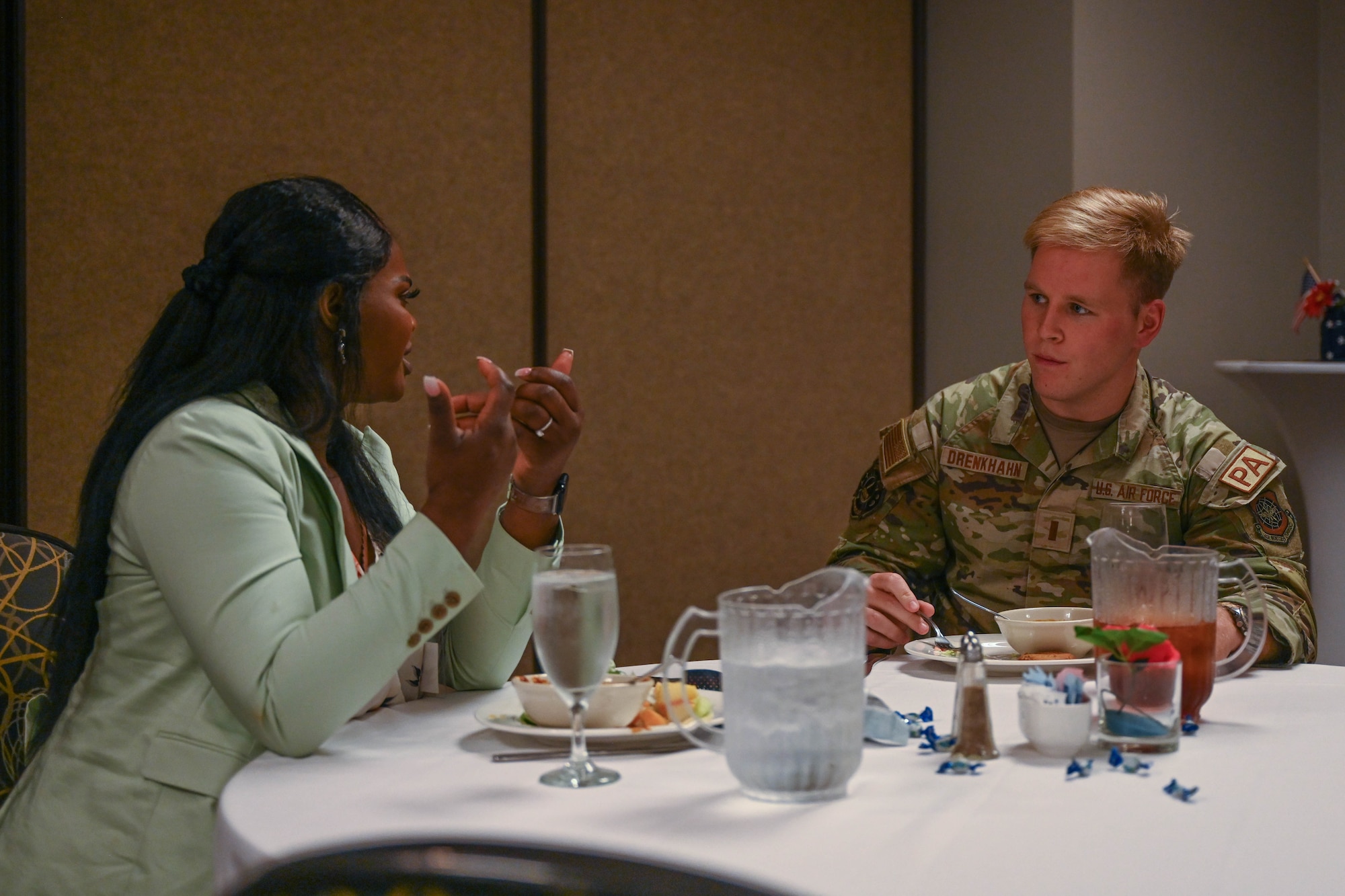A woman eats food with a man in uniform