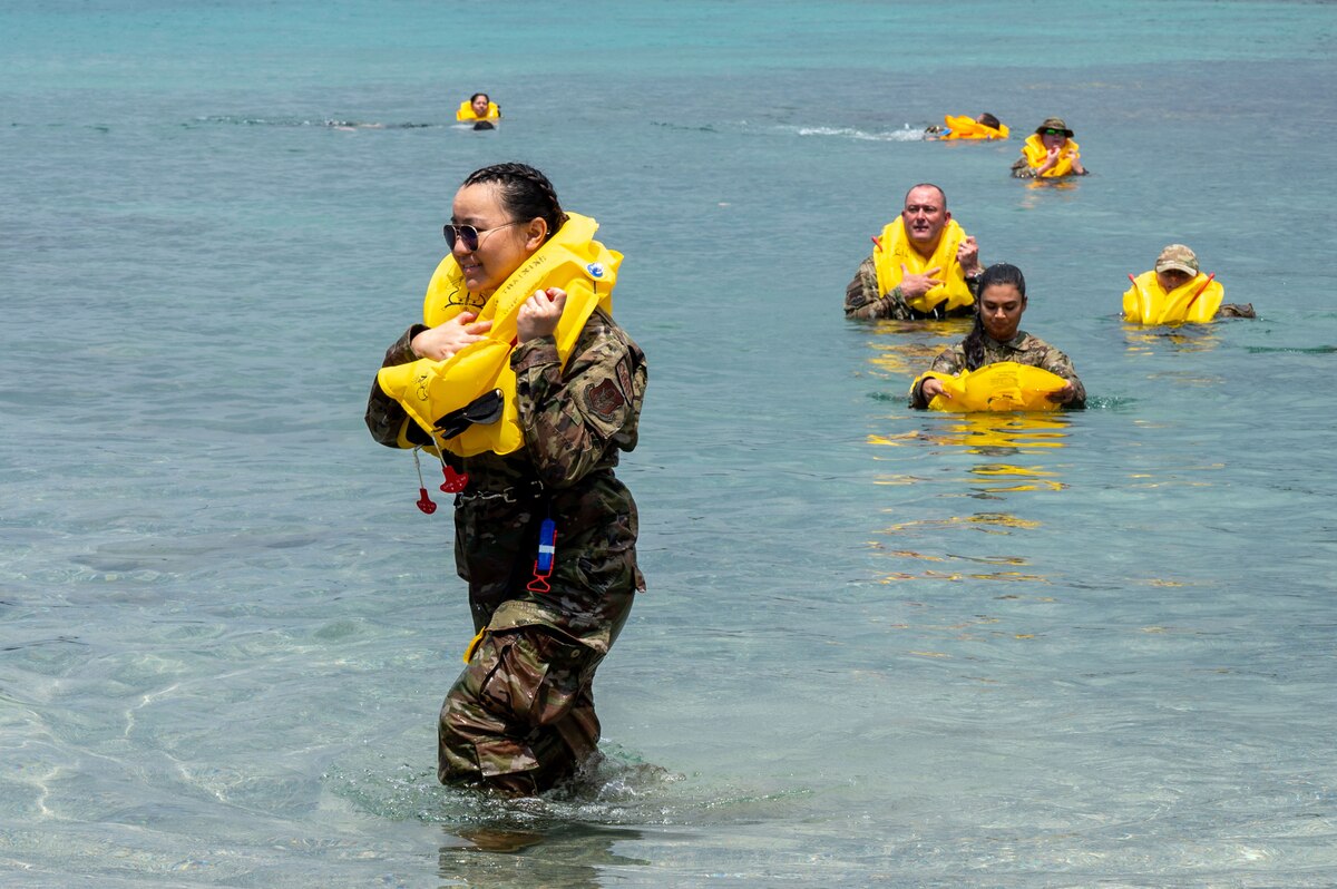 people in military uniforms wear life vests and swim to shore from the water